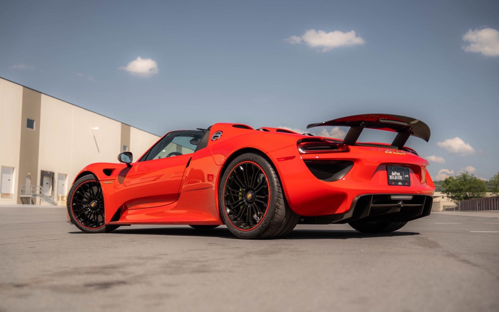 A red Porsche 918 outside a building